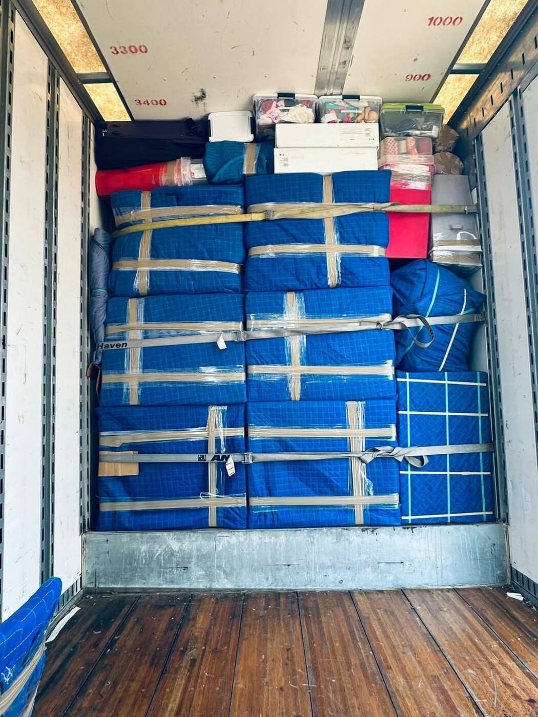 Moving truck interior fully loaded wall-to-wall with blue blanket-wrapped household goods — DFW