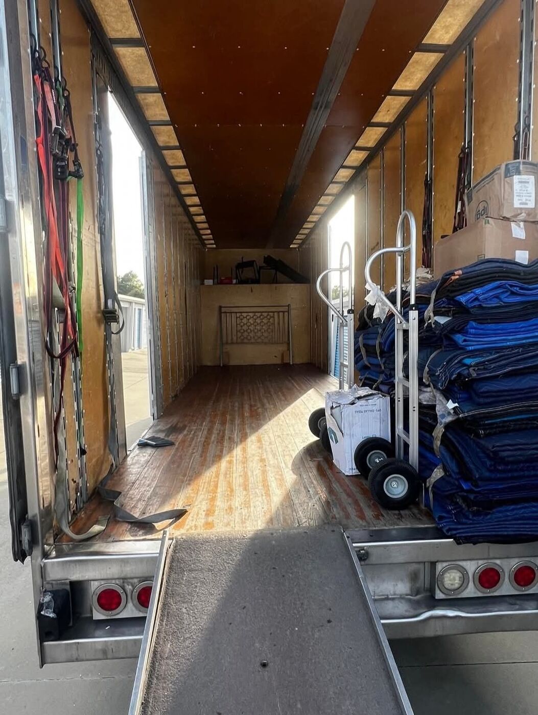 Moving truck interior showing ramp, dolly, and stacked blue moving blankets ready for a job — DFW, Texas