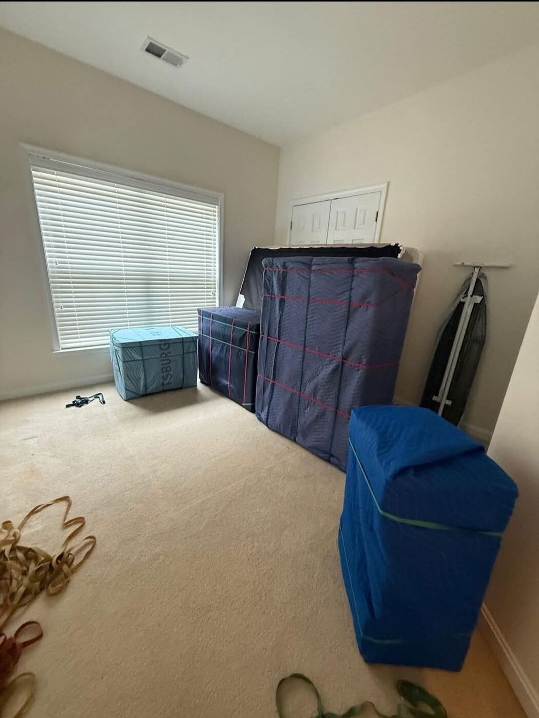 Blue blanket-wrapped dresser, headboard and wardrobe box staged in bedroom ready for pickup — One World Van Lines Allen, TX DFW professional movers