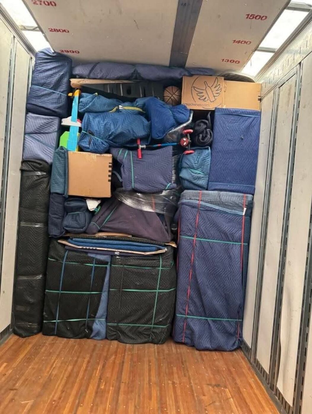 Moving truck packed wall-to-wall with blue blanket-wrapped mattresses, furniture, rolled rugs and sports items — One World Van Lines Frisco, TX DFW Metroplex