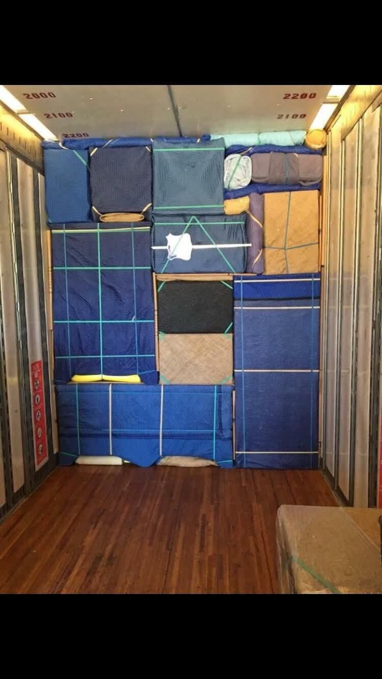 Moving truck interior packed wall-to-wall with blue moving blankets secured by green and white straps — One World Van Lines Mesquite, TX DFW Metroplex professional movers
