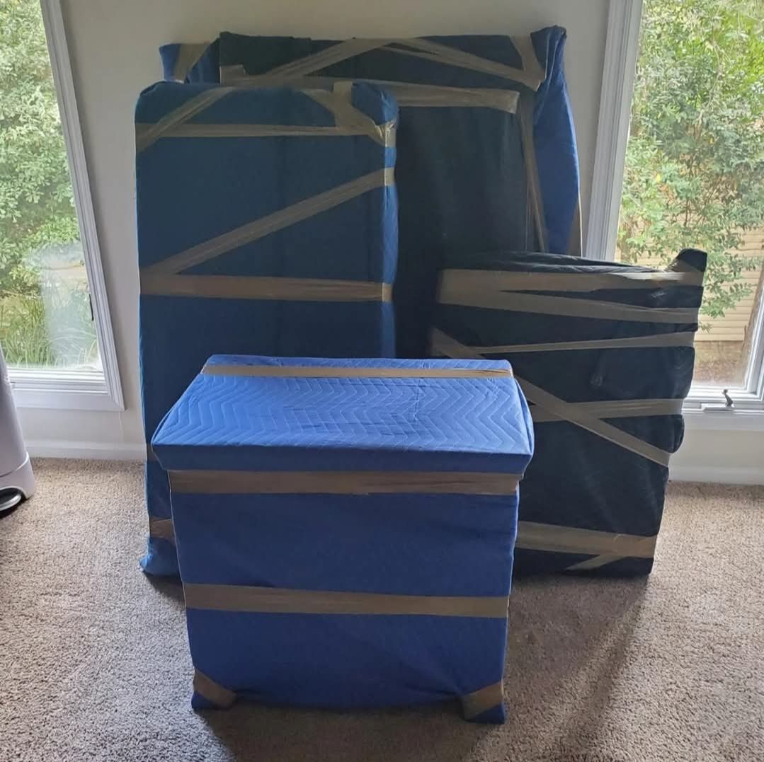 Blue moving blanket-wrapped and taped furniture staged inside home ready for transport — One World Van Lines Austin, TX movers