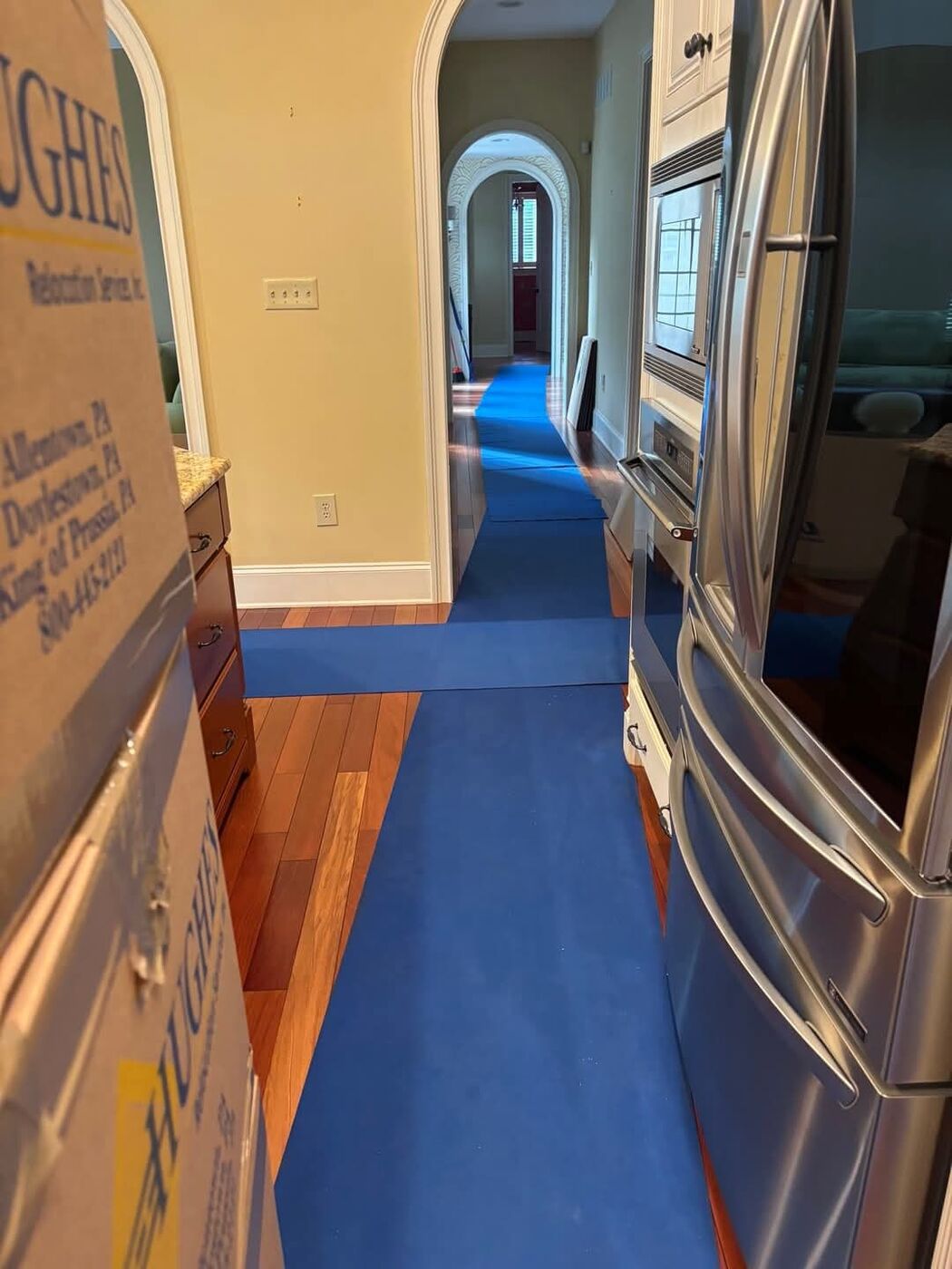 Blue floor protection runners covering hardwood floors throughout luxury home hallway during move — One World Van Lines Southlake, TX DFW professional movers