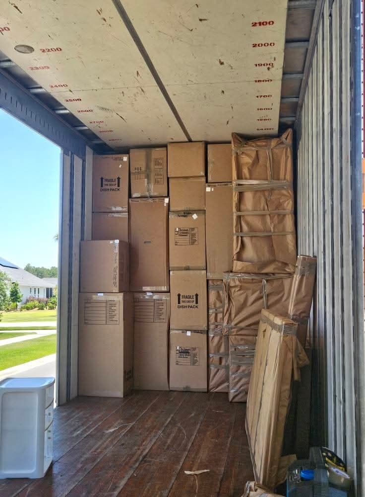 Dish-pack fragile boxes and kraft paper-wrapped specialty items in truck at sunny suburban home — One World Van Lines Pflugerville, Greater Austin TX movers