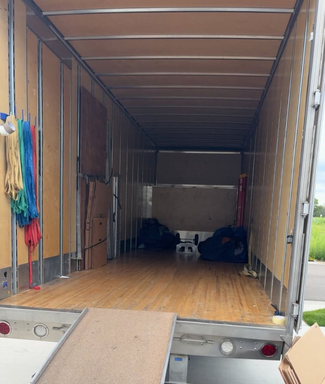 Empty large box truck interior showing full capacity with straps hanging, ramp deployed and cardboard ready for loading — One World Van Lines Allen, TX DFW Metroplex professional movers
