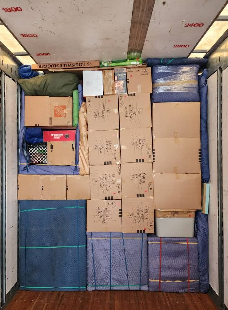 Moving truck tightly packed with Home Depot boxes, hand-labeled boxes, blue blanket-wrapped furniture for long-distance move — One World Van Lines Carrollton, TX DFW headquarters movers