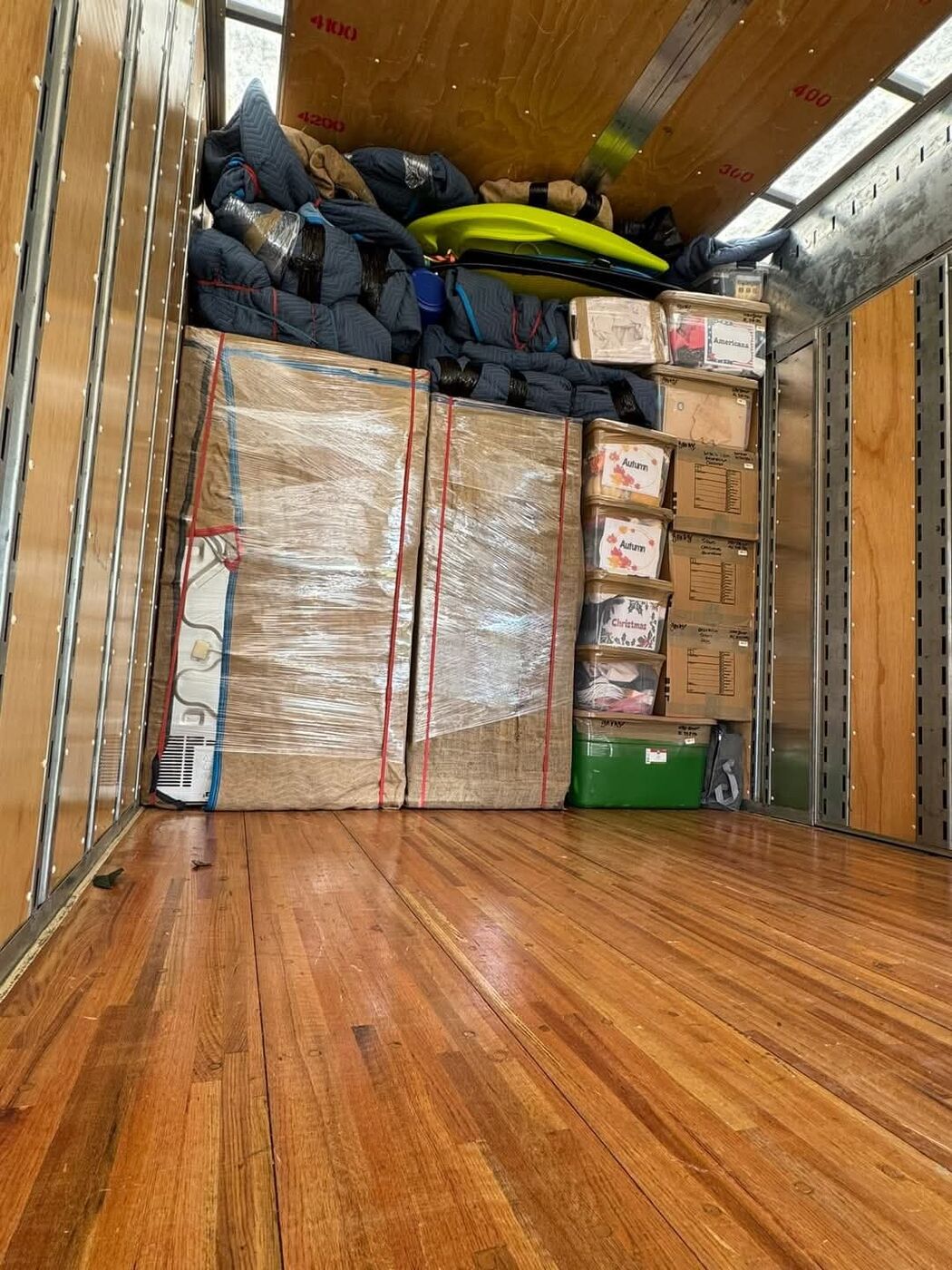 Moving truck loaded with kayak, Autumn and Christmas labeled seasonal boxes, plastic-wrapped flat items and blankets — One World Van Lines Georgetown, TX Greater Austin specialty movers