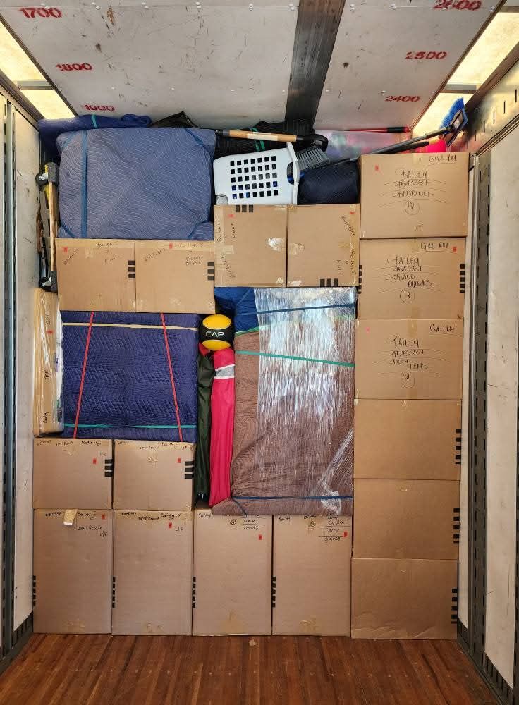 Moving truck interior fully loaded with hand-labeled boxes, blue blanket-wrapped furniture and bungee straps — One World Van Lines North Richland Hills, TX DFW Metroplex movers