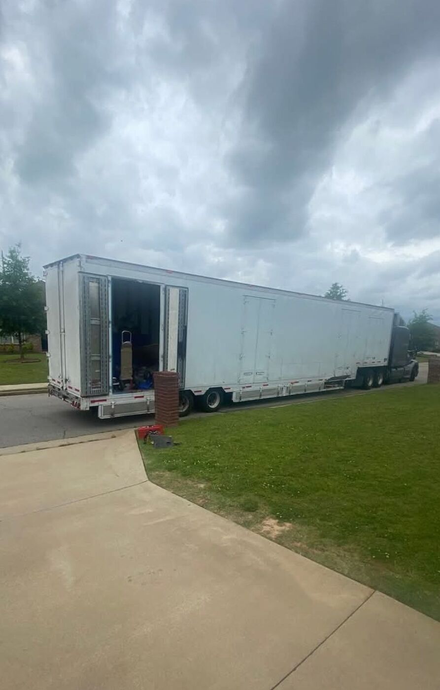 Large white semi-trailer long-distance moving truck parked at suburban neighborhood driveway on overcast day — One World Van Lines Forney, TX DFW Metroplex long-distance movers