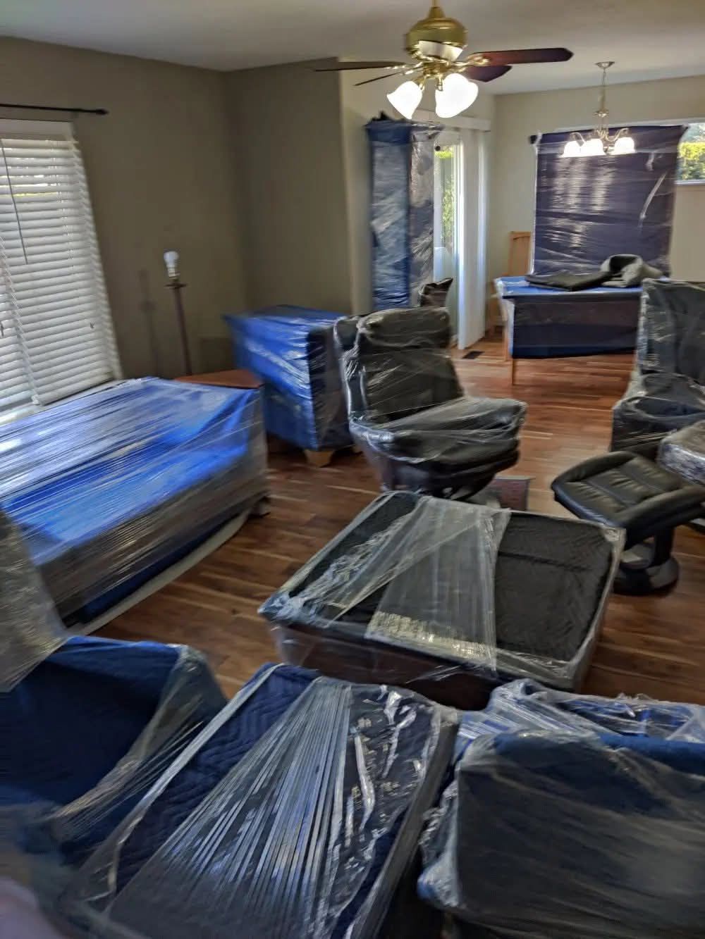 Living room staged for move with plastic-wrapped recliners, mattresses, armoire and ceiling fan home ready — One World Van Lines Flower Mound, TX DFW Metroplex professional movers