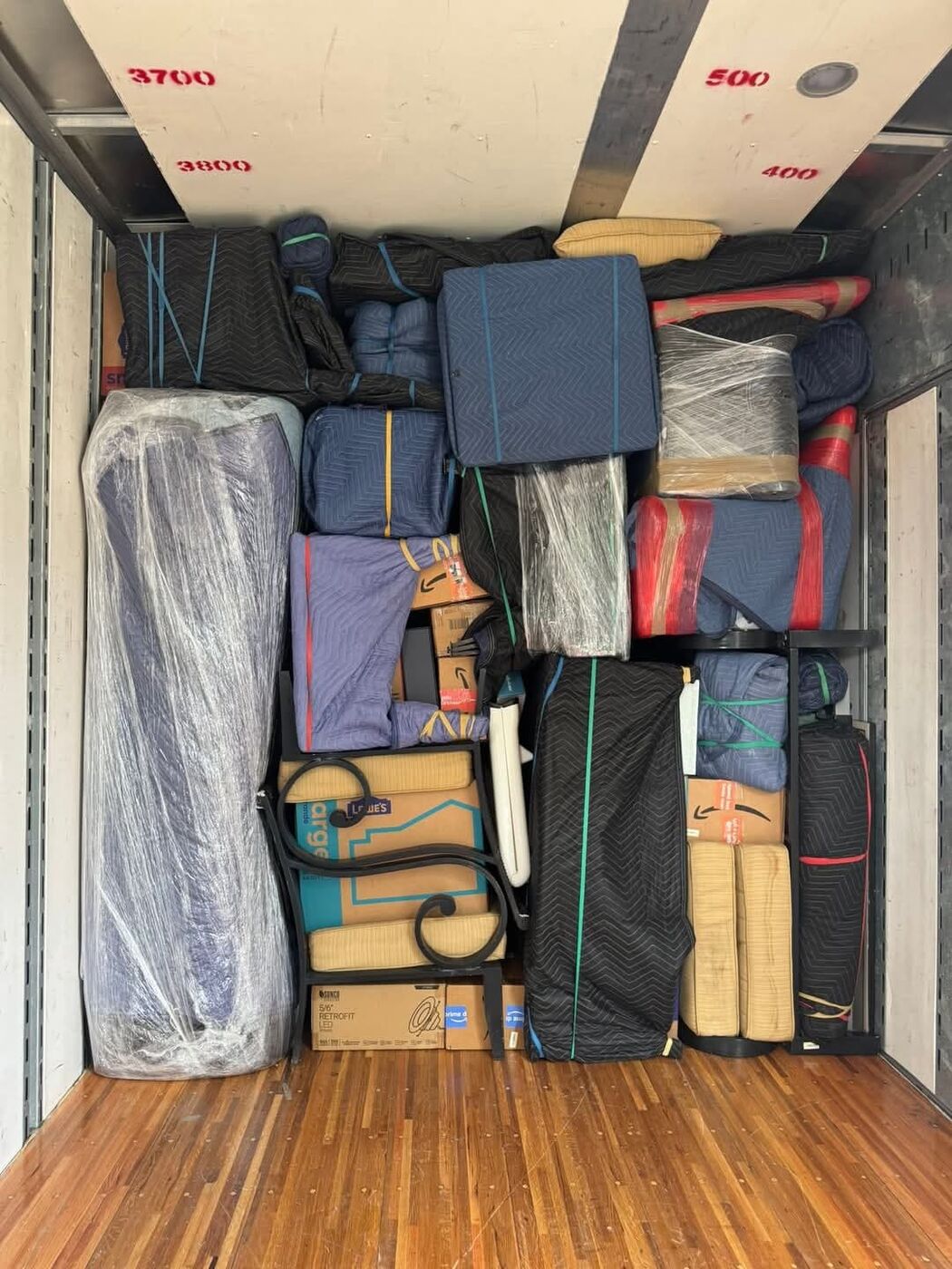 One World Van Lines moving truck packed floor-to-ceiling with blue moving pads and plastic-wrapped mattresses — Dallas, TX residential movers