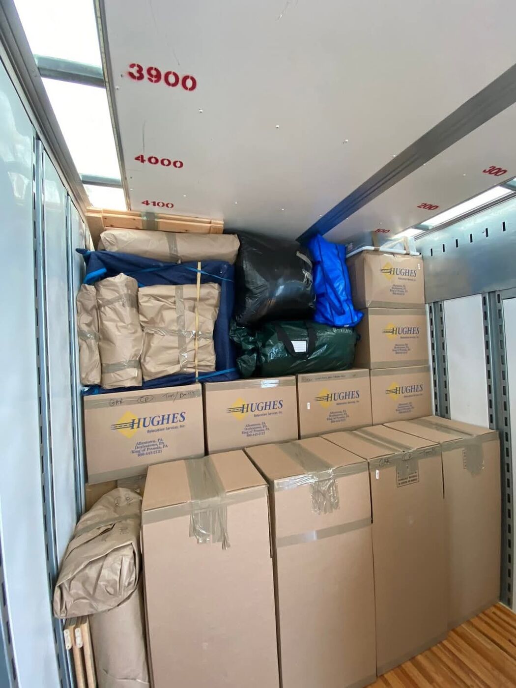 Paper-wrapped items and wardrobe boxes loaded in moving truck — One World Van Lines Euless, TX DFW Metroplex professional movers