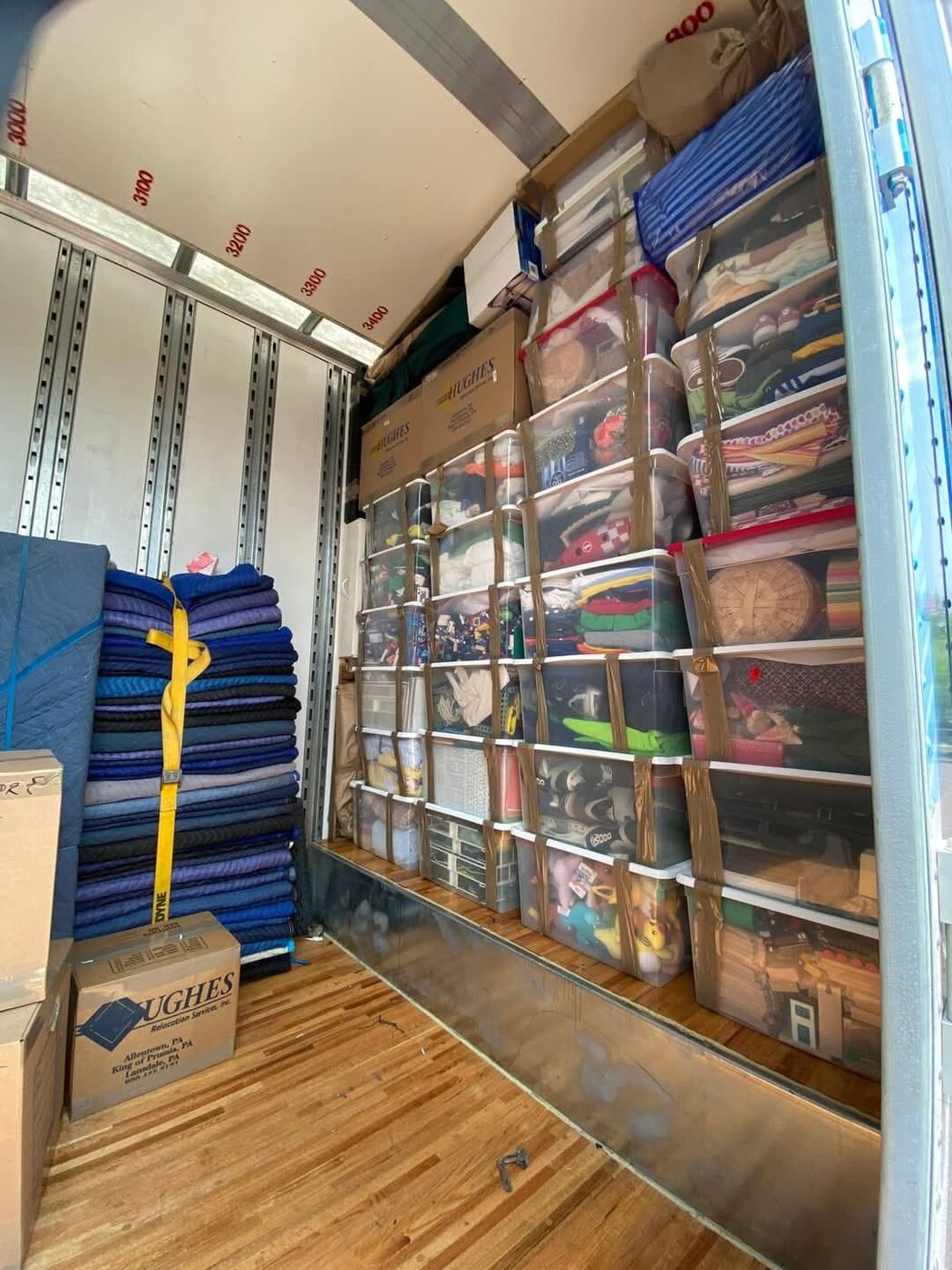 Organized clear plastic storage bins and household items stacked in moving truck — One World Van Lines Greater DFW TX movers