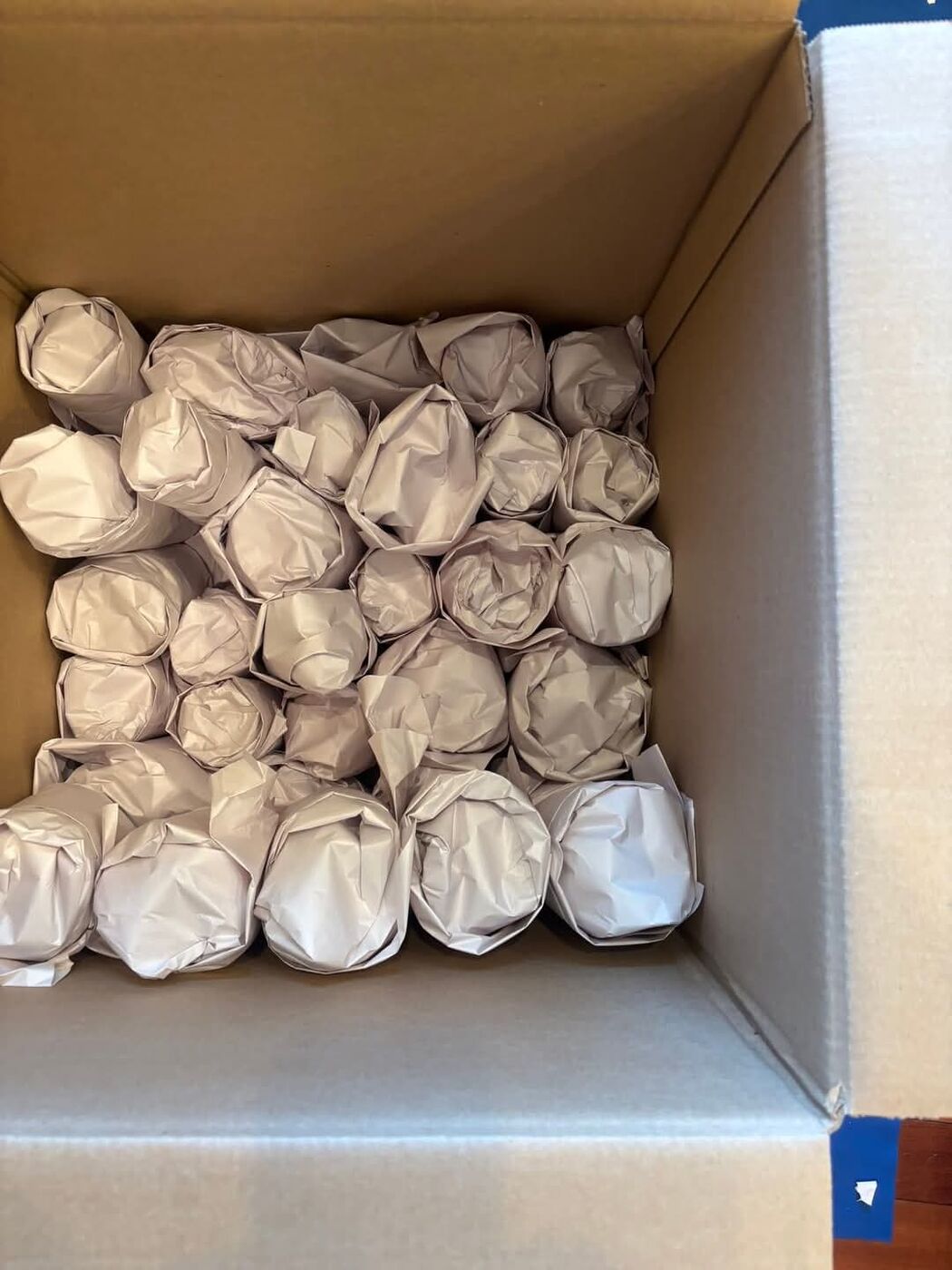 Paper-wrapped dishes and glassware neatly packed inside cardboard box — One World Van Lines professional fragile packing service Dallas, TX