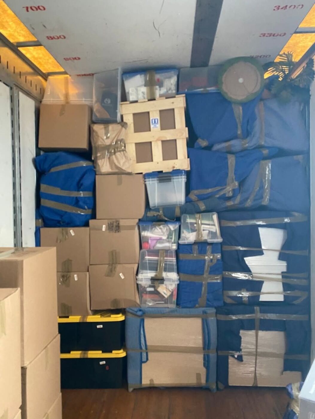 Moving truck packed with clear plastic bins, wooden crate, blue bags and specialty items secured with straps — One World Van Lines Grapevine, TX DFW