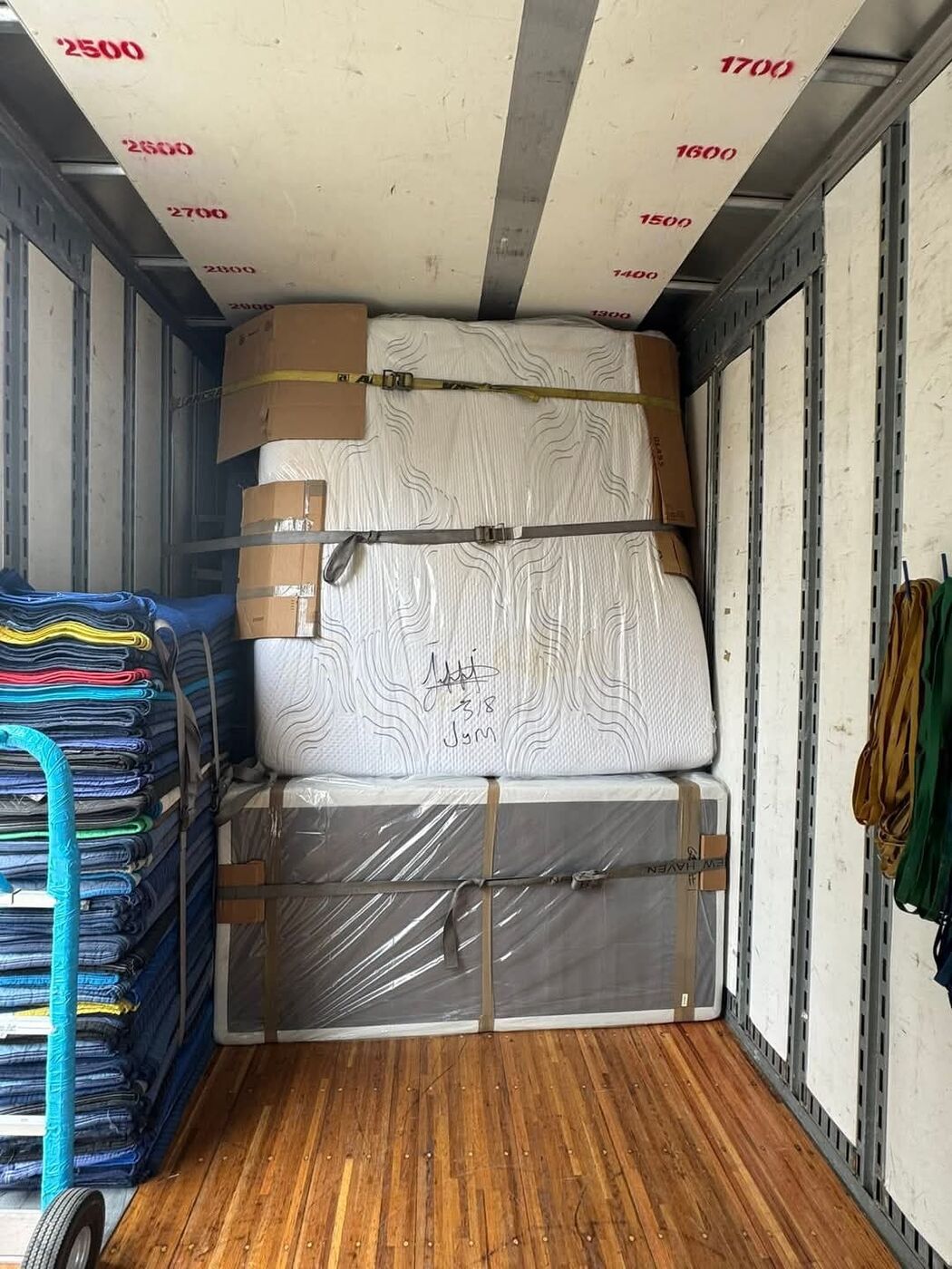 Three stacked mattresses and box spring secured with yellow ratchet straps and gray ratchet belt in moving truck — One World Van Lines Plano, TX DFW Metroplex specialty movers