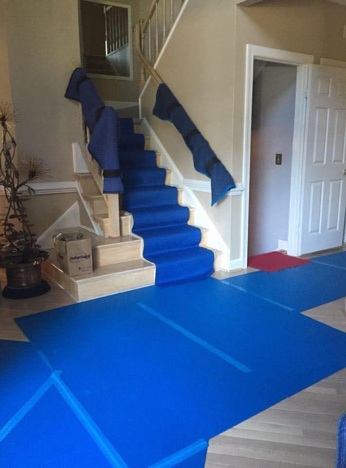 Home foyer staircase fully protected with blue carpet runner on steps and hardwood floor pads on move day — One World Van Lines McKinney, TX DFW Metroplex professional movers