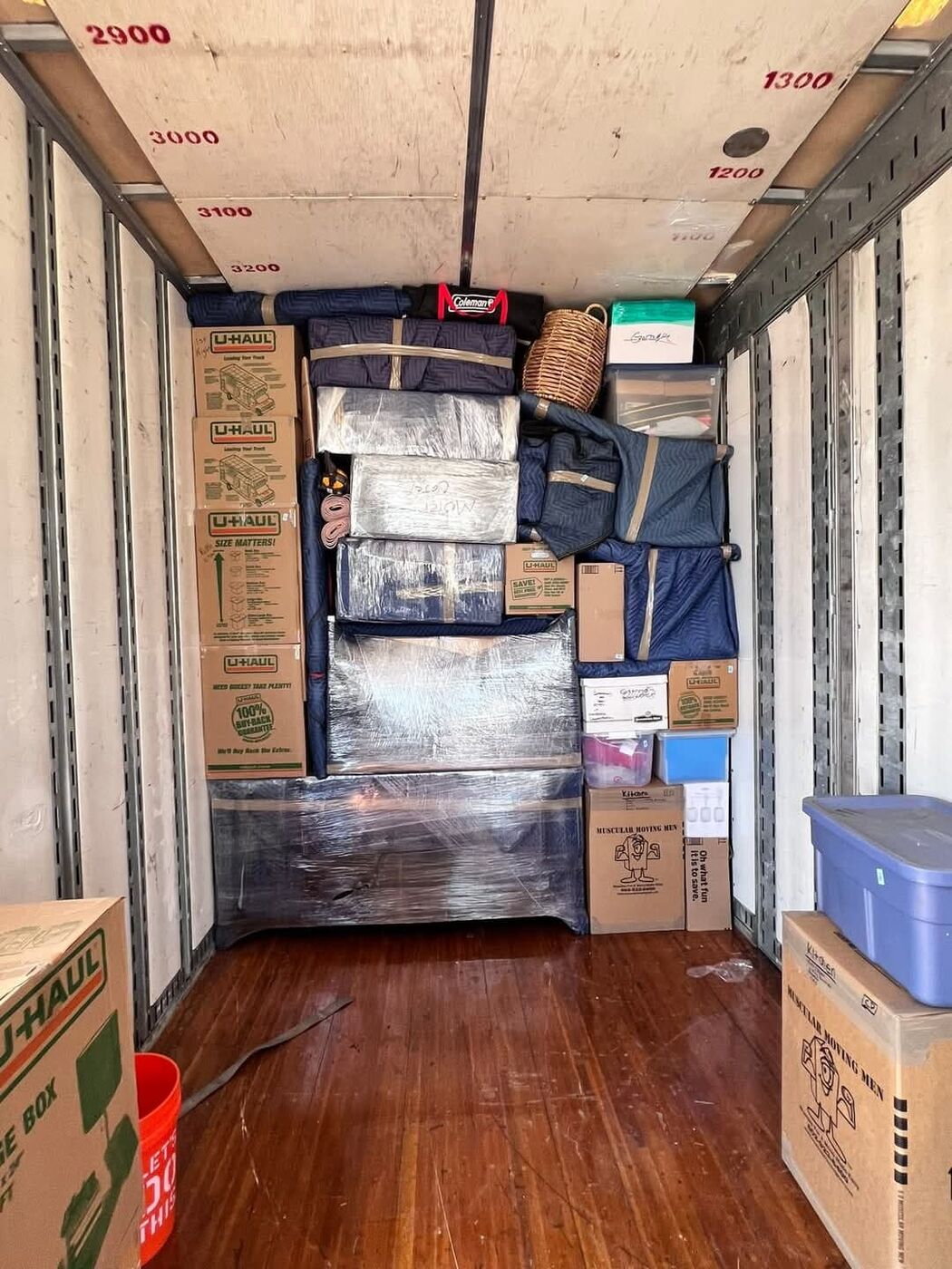 U-Haul boxes and plastic-wrapped dresser furniture secured in moving truck — One World Van Lines Haltom City, TX DFW Metroplex professional movers