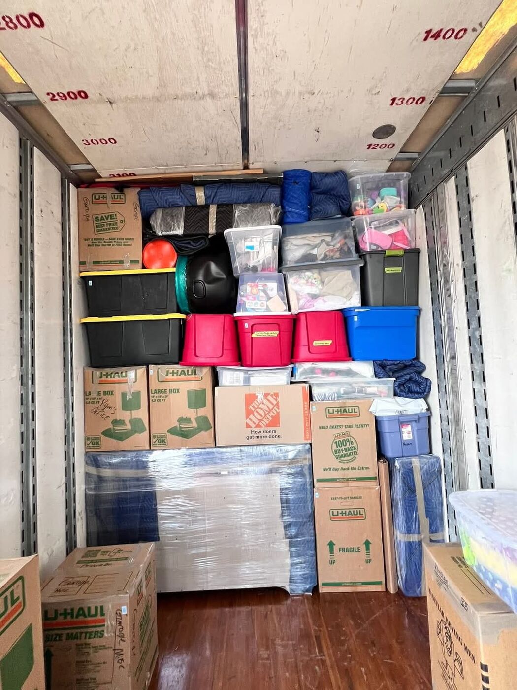 U-Haul large boxes, Home Depot box, colorful plastic tubs and plastic-wrapped mattress packed in moving truck — One World Van Lines Hurst, TX DFW Metroplex movers