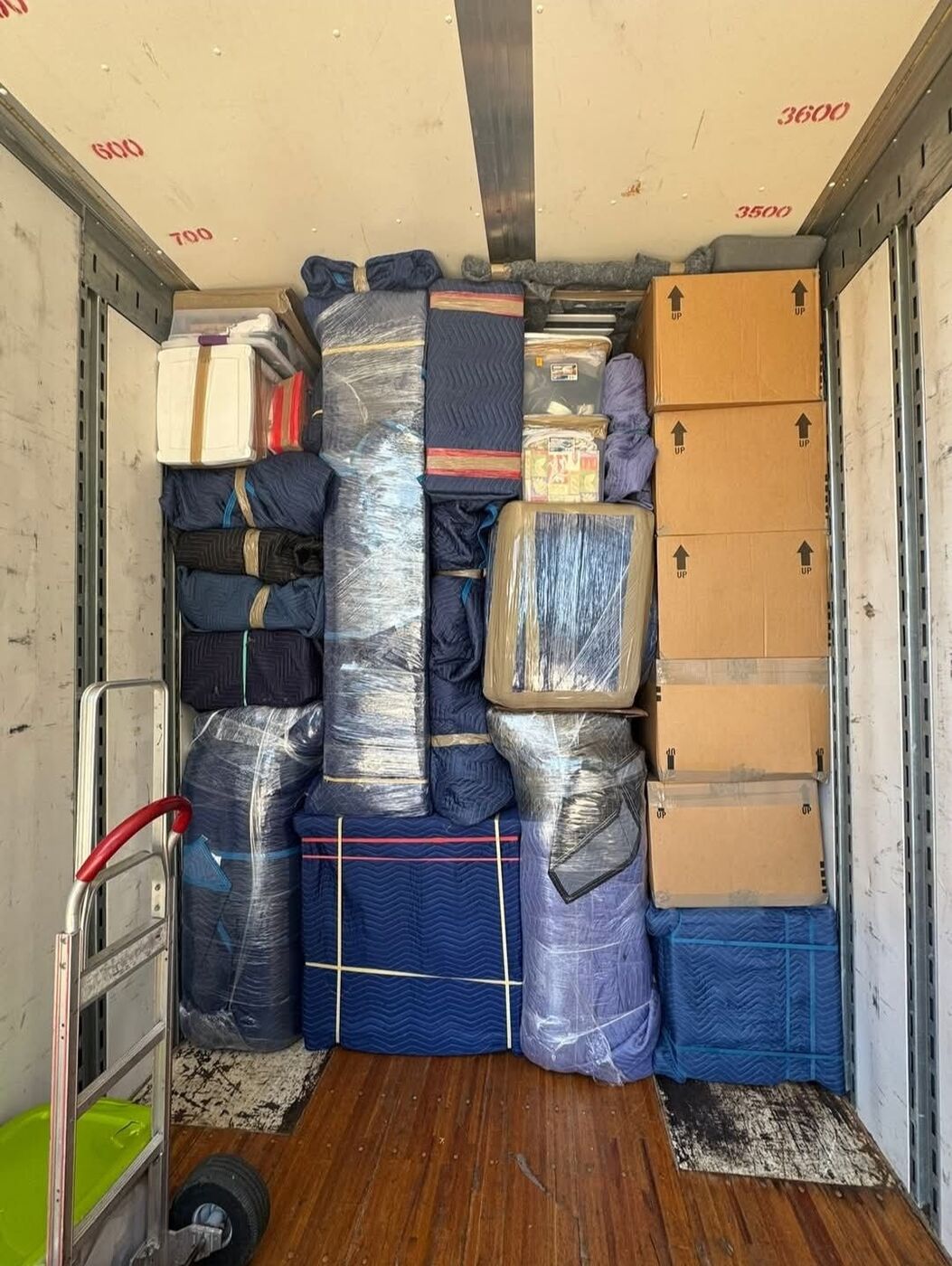 Packed moving truck interior with blue blankets, labeled boxes, and hand truck dolly — DFW professional movers