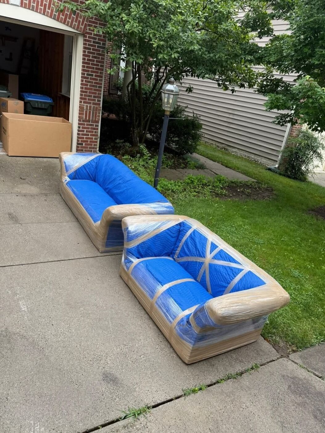 Sofas wrapped in plastic and moving blankets on driveway — DFW moving service